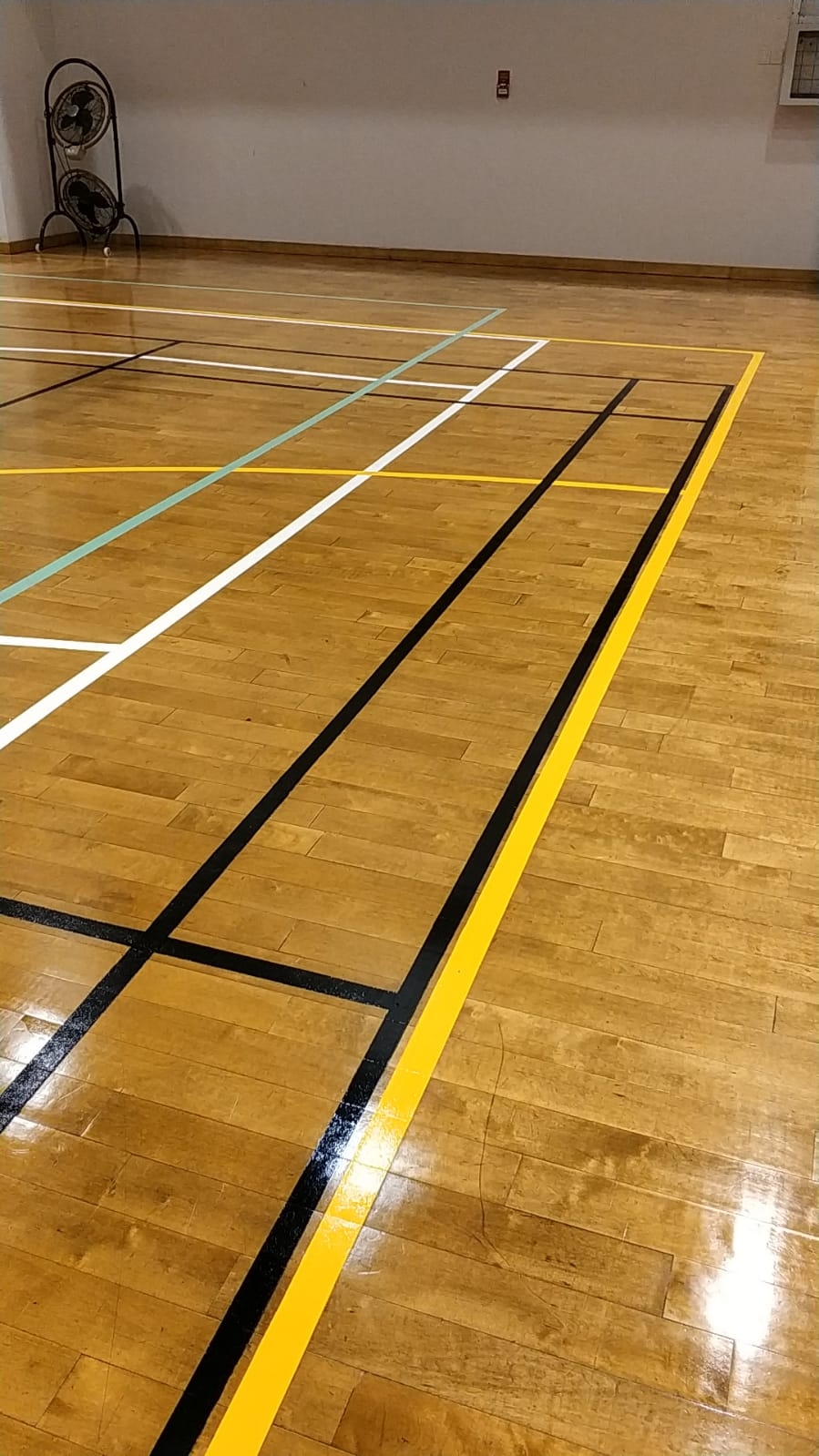 Completed yellow and black badminton and volleyball game lines on the timber sports floor